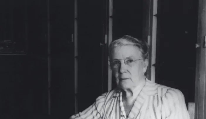 Photograph of a stout middle-aged woman seated at her desk, writing