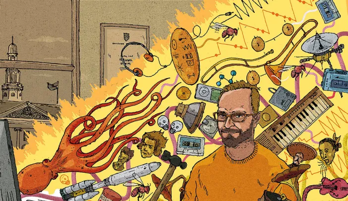 A professor sits at a computer whose screen is shooting out a beam of light filled with all sorts of animals and musical instruments