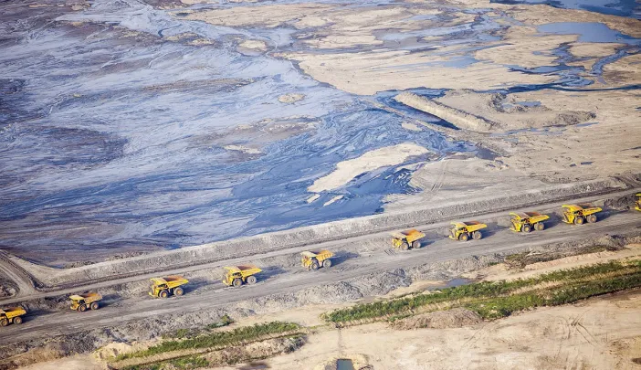 Huge dump trucks lined up in 2012 to transport tar sand from a surface mine, Fort McMurray, Alberta 