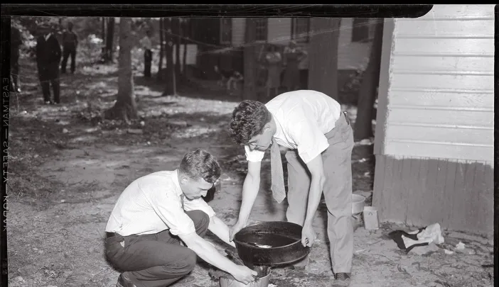 Forensic pioneer Joseph T. Walker (at left) collects blood and scraps of flesh from the bathtub drain of a 1936 murder victim.