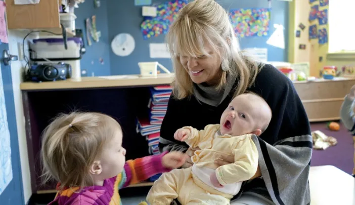 Mary Kinsella Scannell, vice president for early education and care, plays with baby Kinsey Ferraguto and toddler Margot Vorhees.