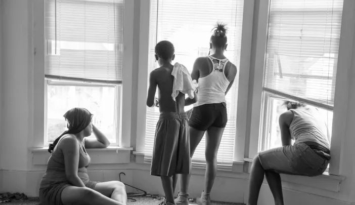 While being evicted from her Milwaukee apartment, Danielle Shaw (left) and relatives wait until the movers carrying down her refrigerator and stove are no longer blocking the stairwell. 