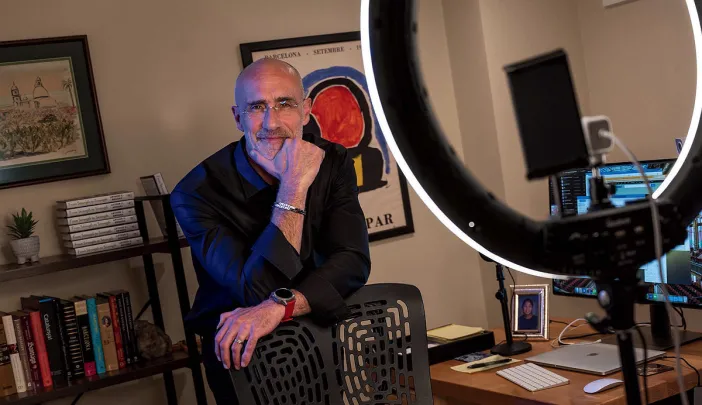 Arthur Brooks stands behind a chair in his office, smiling