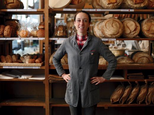 Apollonia Poilâne standing in front of rows of fresh-baked loaves at her family's flagship bakery