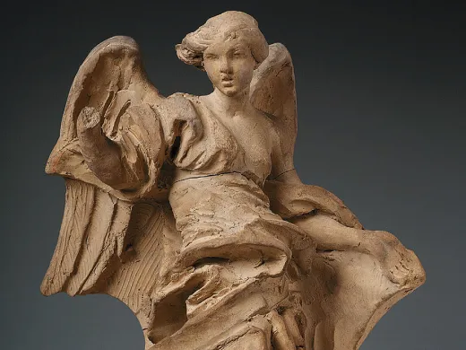 A clay sculpture of a robed angel. 