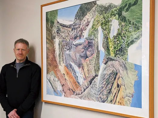 Darren Sears stands to the left of his framed work "Summit"