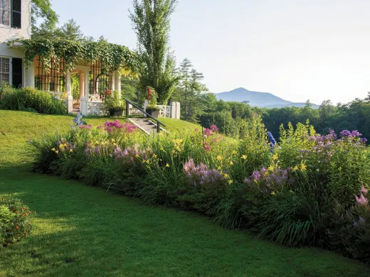 Garden view of Aspet, with vibrant flower beds and Mount Ascutney in the background.