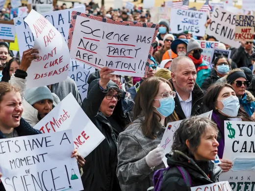 Crowd at Boston science rally holding protest signs opposing research funding cuts