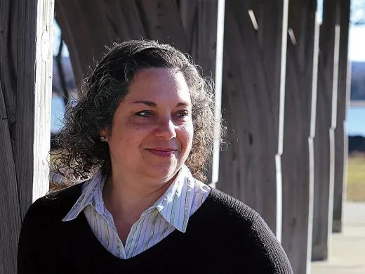Catherine Zipf smiling, wearing striped shirt and dark sweater outdoors.