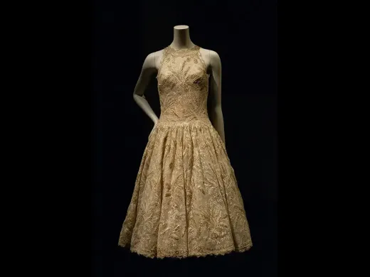 A vintage golden dress with a fitted bodice and flared skirt displayed on a mannequin.