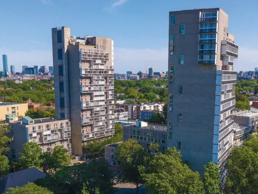 Aerial view of modern high-rise buildings surrounded by greenery and city skyline.