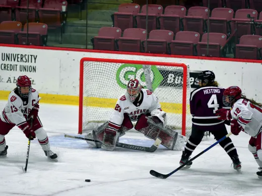 Photograph of several players competing for the puck in front of the Harvard goal