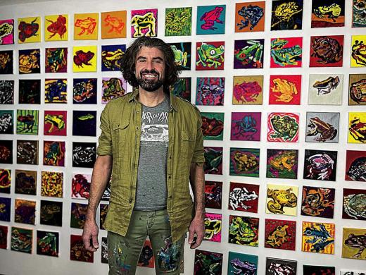 Bradley Scott Davis standing in front of a wall of frog paintings