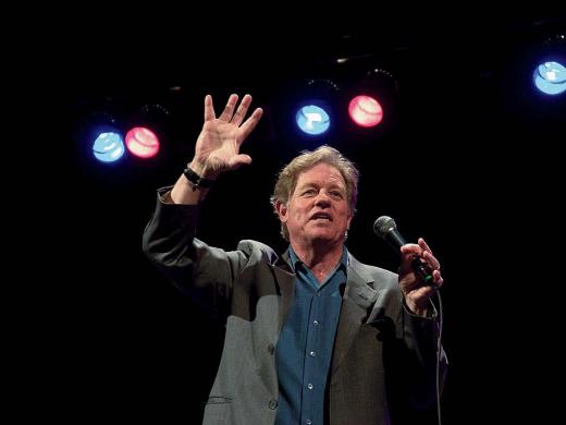 Jimmy Tingle holding a microphone and performing on stage 