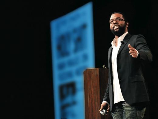 With a front page from <i>The Onion</i> projected in the background, Thurston emcees the 2009 SXSW Interactive Web Awards.