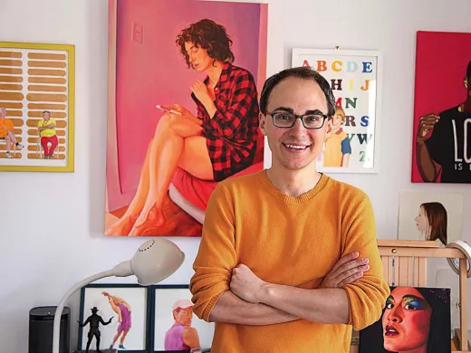 David Andersson standing among his colorful painted portraits