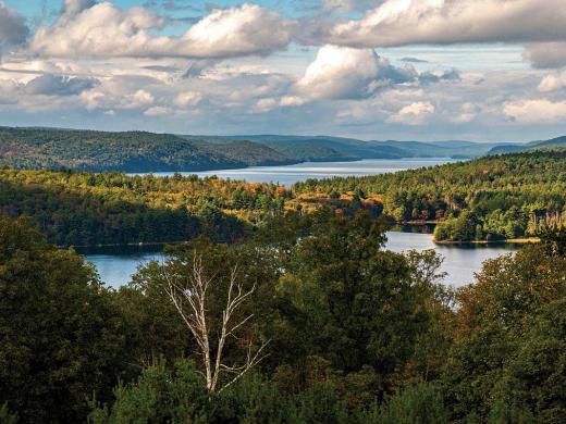 sweeping aerial view of blue sky and Quabbin Reservoir water and mountains 