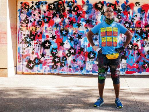 Anwar Floyd-Pruitt standing off a red, white, and blue mural he painted after George Floyd’s death. Floyd's right hand is bandaged after he was attacked while painting the mural.