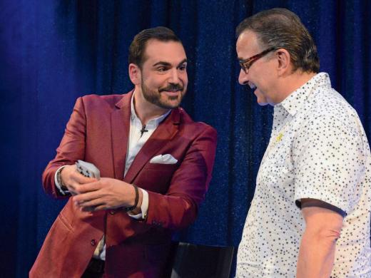 A magician and comedian doing a card trick with an audience member