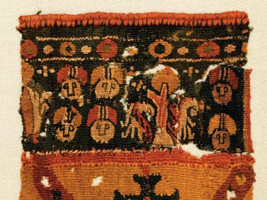 A colorful Byzantine funerary tunic fragment depicts faces and vegetal patterns with a border of gemstones.