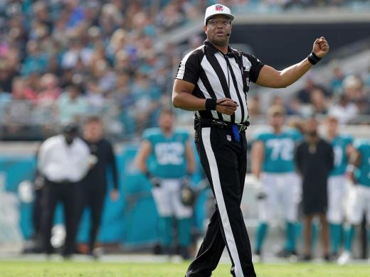 NFL referee Ron Torbert in uniform on the football during a game