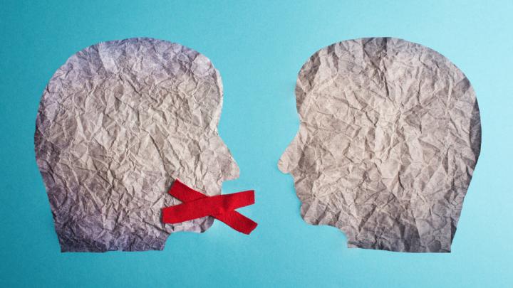Two heads made of paper with red x over mouth of one head