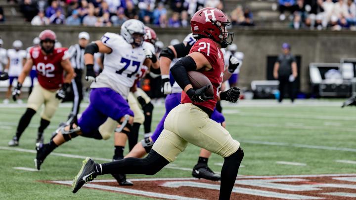 Harvard football player 21 runs with ball towards a touchdown with St. Thomas players pursuing