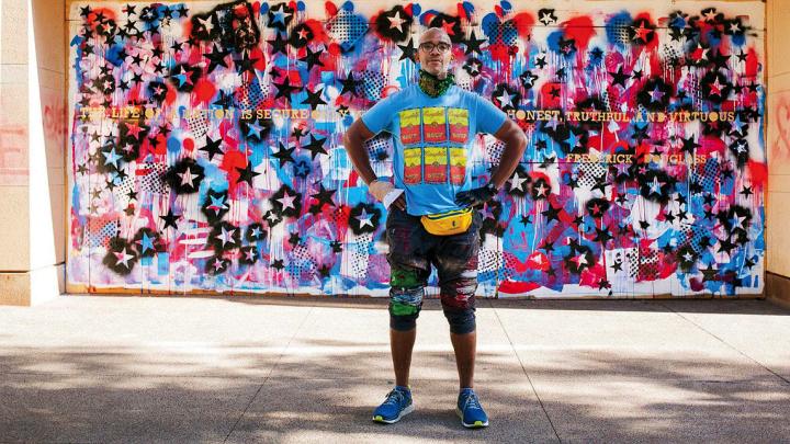 Anwar Floyd-Pruitt standing off a red, white, and blue mural he painted after George Floyd’s death. Floyd's right hand is bandaged after he was attacked while painting the mural.