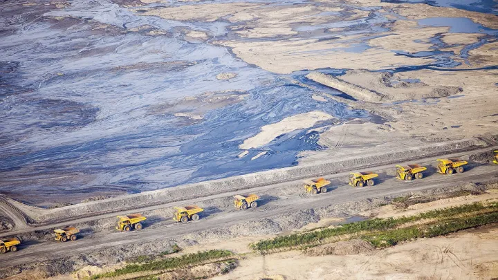 Huge dump trucks lined up in 2012 to transport tar sand from a surface mine, Fort McMurray, Alberta 