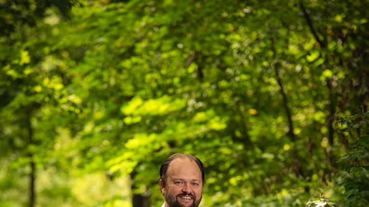 Ross Douthat standing in a wooded park