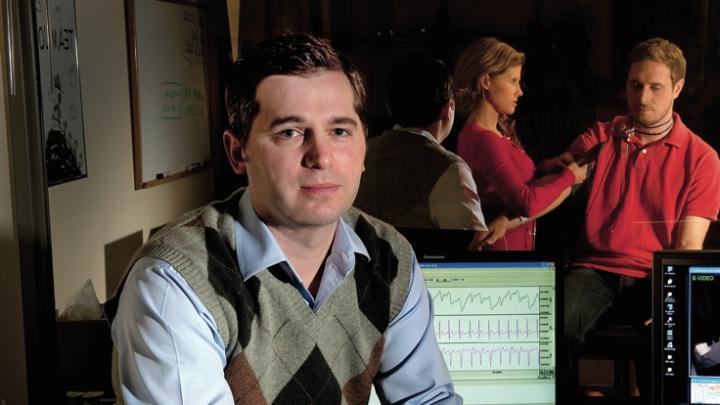 Matthew Nock sits in his lab’s control room, where researchers record subjects’ behavioral and physiological responses during experiments. For example, they might measure whether people who engage in self-injury show greater emotional distress, in response to frustrating tasks, than people who do not. (Nock’s lab manager and a postdoctoral fellow are seen in the adjoining room through one-way glass.)