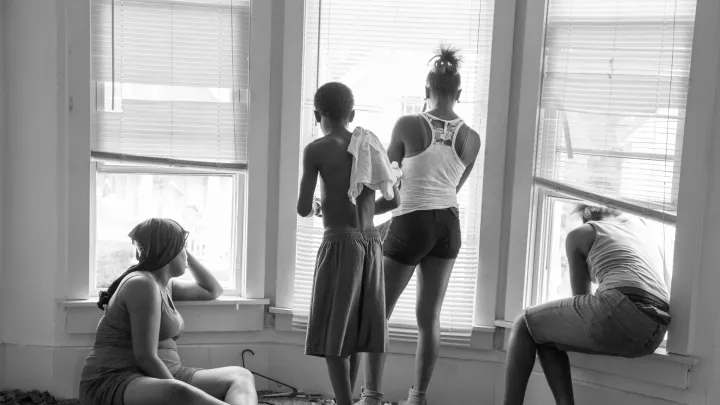 While being evicted from her Milwaukee apartment, Danielle Shaw (left) and relatives wait until the movers carrying down her refrigerator and stove are no longer blocking the stairwell. 