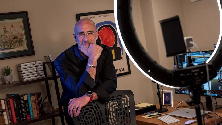 Arthur Brooks stands behind a chair in his office, smiling