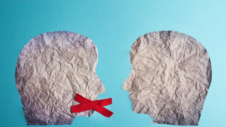 Two heads made of paper with red x over mouth of one head