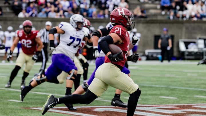 Harvard football player 21 runs with ball towards a touchdown with St. Thomas players pursuing