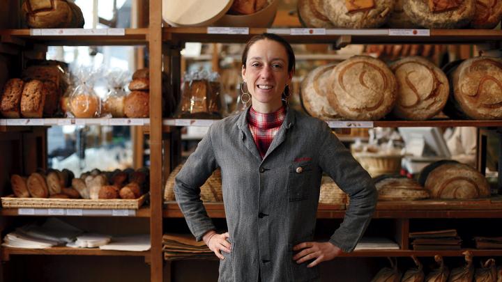 Apollonia Poilâne standing in front of rows of fresh-baked loaves at her family's flagship bakery