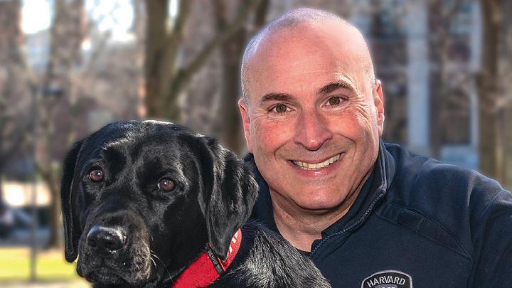Harvard police officer Steven Fumicello poses with black Labrador retriever Sasha. 