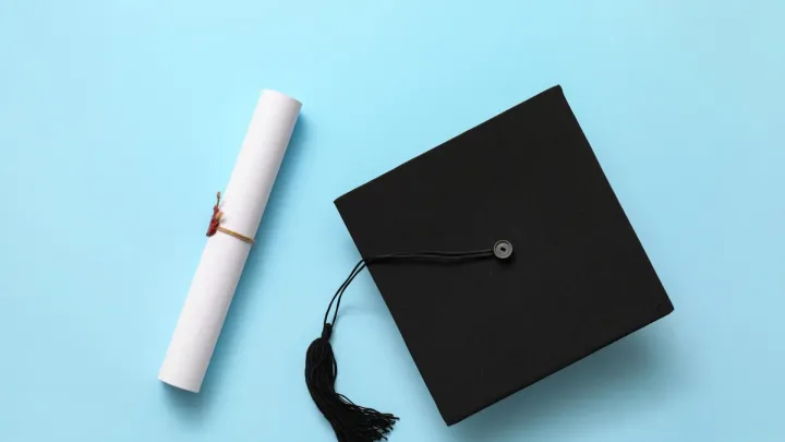 Graduation hat and diploma on color background