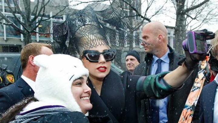 Lady Gaga poses with a fan near the Science Center before the Sanders Theatre panel.