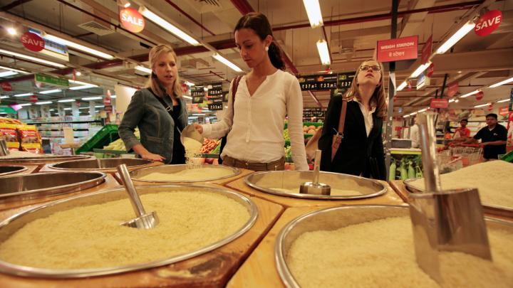 Kara Scarbrough, Alma Donohoe, and Edison examine the many varieties of rice for sale at this hypermarket.