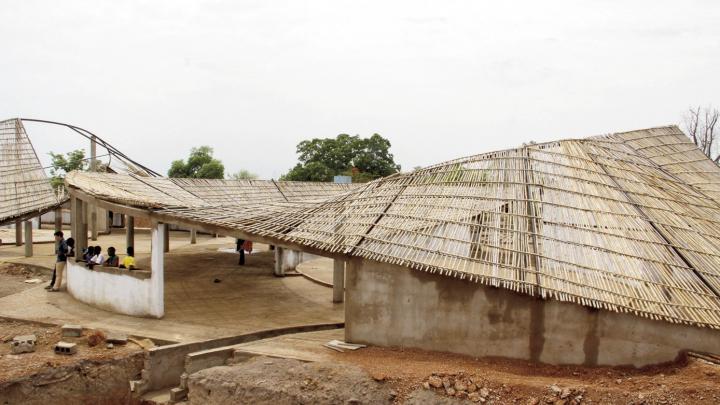 The undulating roof, constructed of local bamboo and thatch, is designed to catch rainwater for community use.