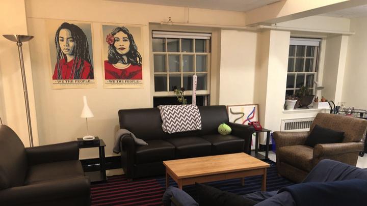 Photograph of the author's Harvard dorm room with chairs, sofa, posters
