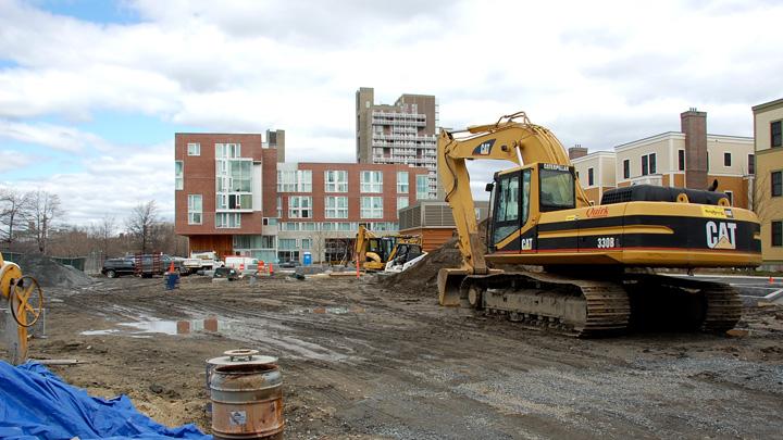 A public park is under construction at the intersection of Memorial Drive and Western Avenue. In the background, recently completed 10 Akron Street houses graduate students and other University affiliates.