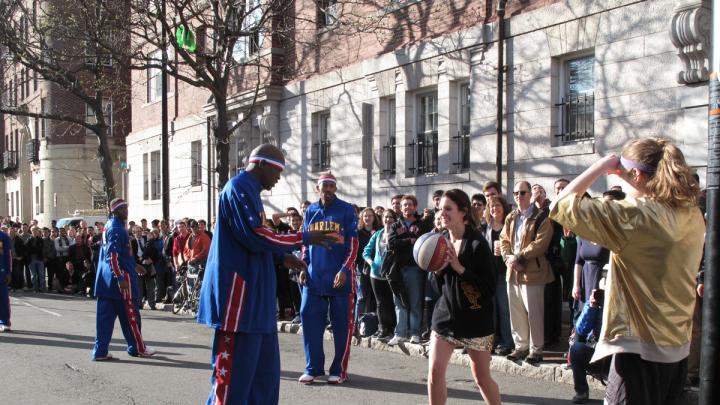 A female Lampoon member wearing a gold sequined dress passes the ball to a teammate.