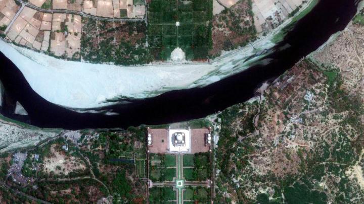 A satellite view shows the main monument at the center, with the gardens in front (bottom) and the Yamuna River behind (top). Few visitors realize that there is another garden across the river. The Mehtab Bagh, or Moonlight Garden, contained an octagonal pool that reflected an image of the monument; historians believe the garden, now mostly in ruins, was designed as a viewing place for the monument.