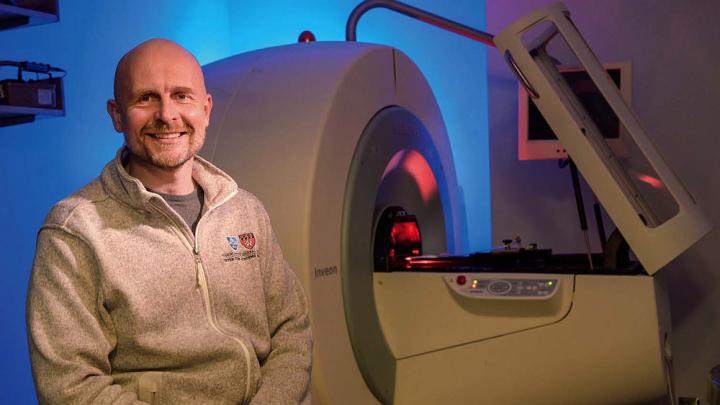 Matthias Nahrendorf seated in front of a PET/CT scanner