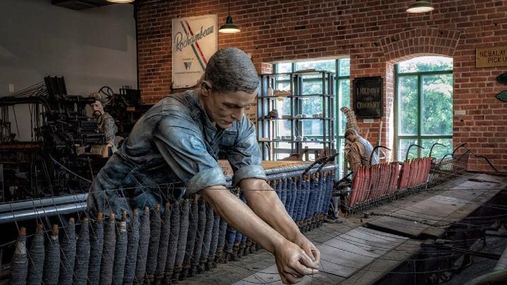 A replica of a textile mill shows life-like statues of workers. 