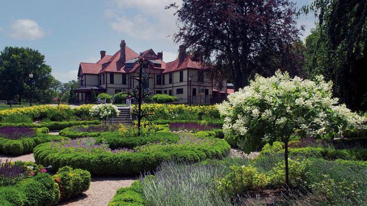 Wide view of formal gardens with a historic mansion in the background