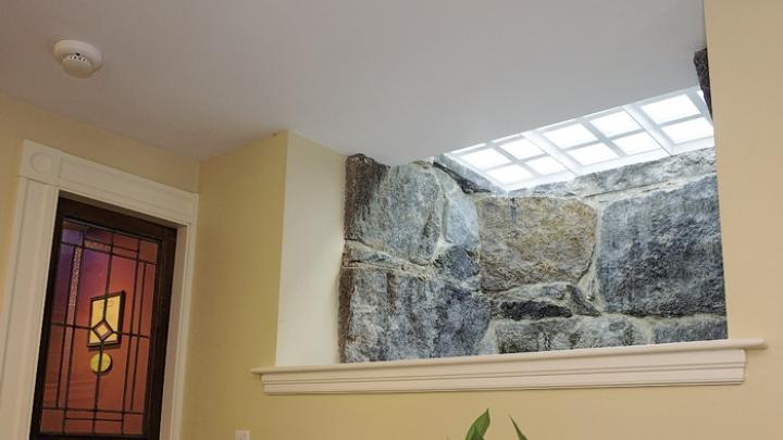 A granite-lined window well at the headquarters of Charlie Allen Restorations Inc. uses frosted glass pavers in the sidewalk to brighten a basement hallway.