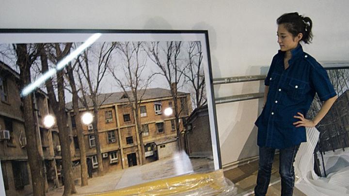 Graduate  student Ren Wei with one of Wang Di’s photographs  at a studio in Beijing. 